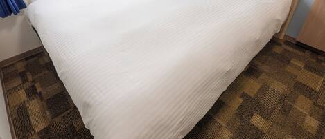A neatly made bed with white linens, a wooden headboard, and a checkered floor pattern.