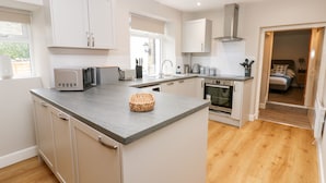 A modern kitchen with white cabinets, a granite countertop, a built-in oven, and a large window. - Hall Garth Cottage (Leyburn)