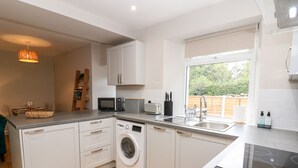 A modern kitchen with a washing machine, microwave, and toaster. - Hall Garth Cottage (Leyburn)