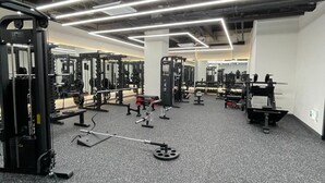 A gym with various weightlifting equipment, mirrors, and a speckled grey floor. - JD Tower Hotel (Seoul)