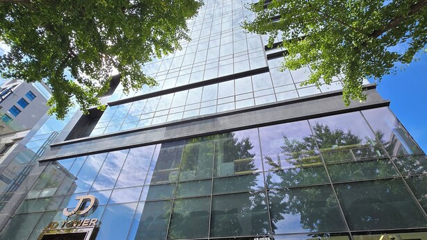 A modern building with a glass facade and a visible logo on the entrance. - JD Tower Hotel (Seoul)