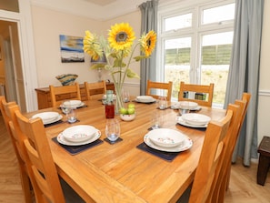 Uma mesa de jantar posta com pratos, copos e um vaso com girassóis.