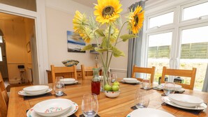 A dining table set for six with plates, glasses, and a vase of sunflowers. - Station Avenue (Sandown)