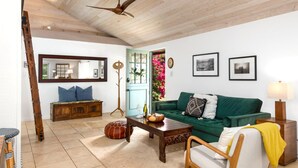 Un salon avec un plafond en bois, un canapé vert, une table basse en bois et une chaise en bois.
