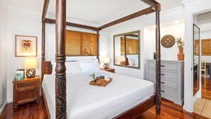 Un lit à baldaquin avec une finition en bois, une table de chevet avec une lampe, un miroir et une commode avec des tiroirs.