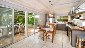 Une cuisine moderne dotée d’un grand îlot central, de meubles en bois et d’un coin repas avec des meubles en osier.