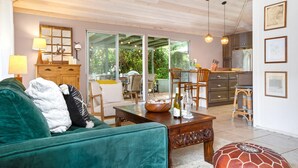 Un salon chaleureux avec un canapé vert, une table basse en bois et un coin repas comprenant des chaises et une table.