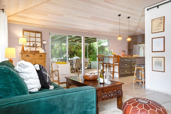 A cozy living room with a green sofa, a wooden coffee table, and a dining area with chairs and a table.