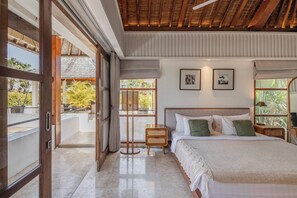 Un dormitorio con una cama grande, cabecera de madera y vistas al exterior a través de una puerta corredera.