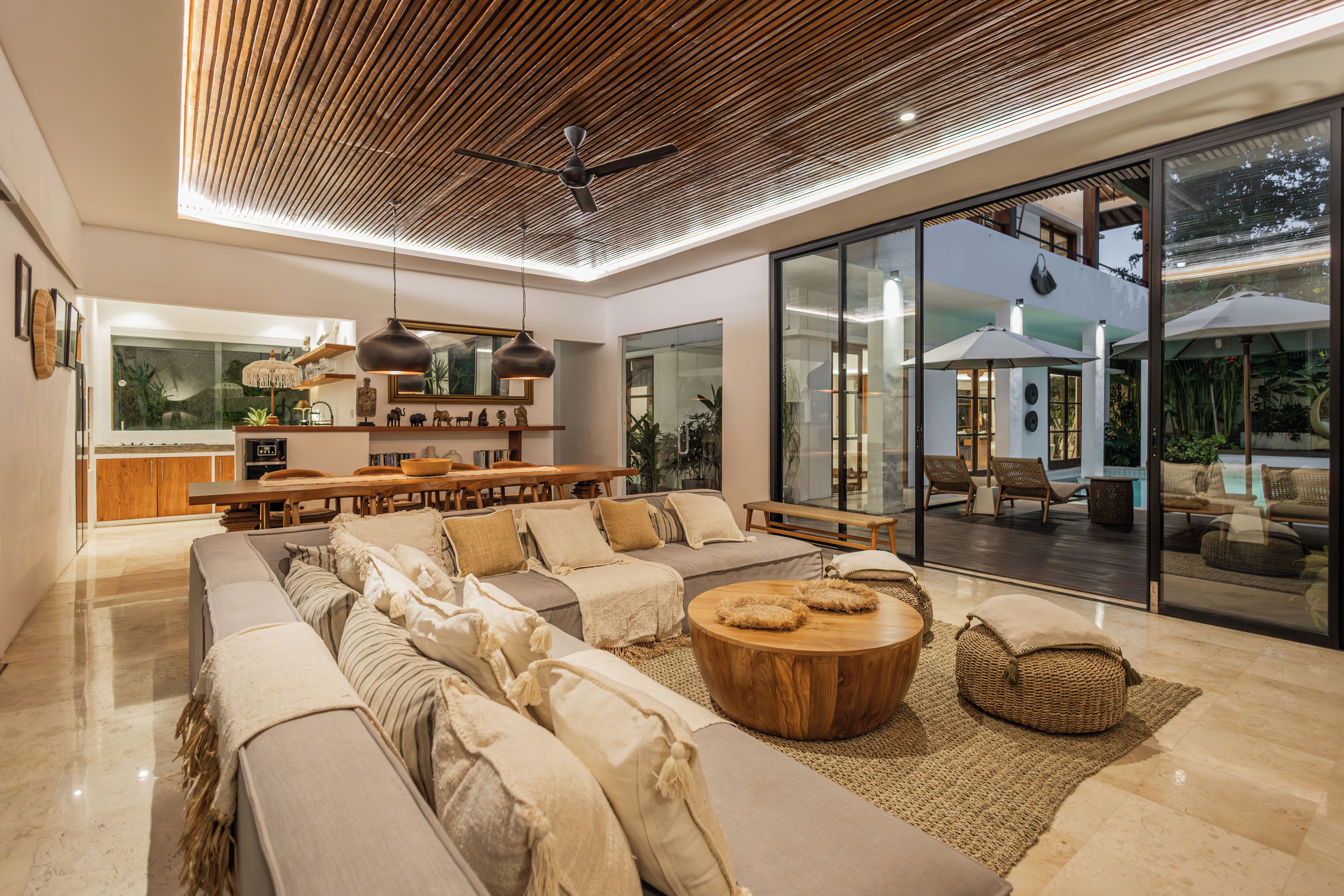 Una sala de estar moderna con un sofá grande, una mesa de centro de madera y un comedor con una mesa y sillas de madera.