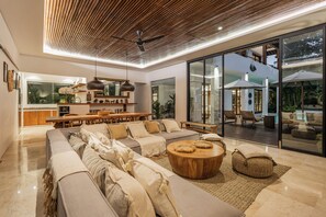 Una sala de estar moderna con un sofá grande, una mesa de centro de madera y un comedor con una mesa y sillas de madera.