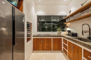 Una cocina compacta con armarios de madera, un refrigerador de acero inoxidable, un ventanal con vistas y una encimera con cafetera.