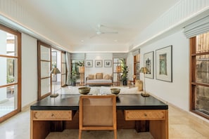 Una habitación amplia con un escritorio grande, un sofá y un ventilador de techo.