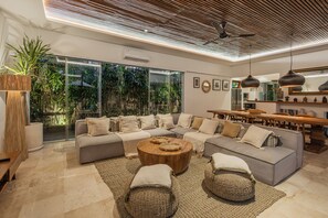 Una sala de estar moderna con un sofá modular, una mesa de centro y un comedor con mesa y sillas de madera.