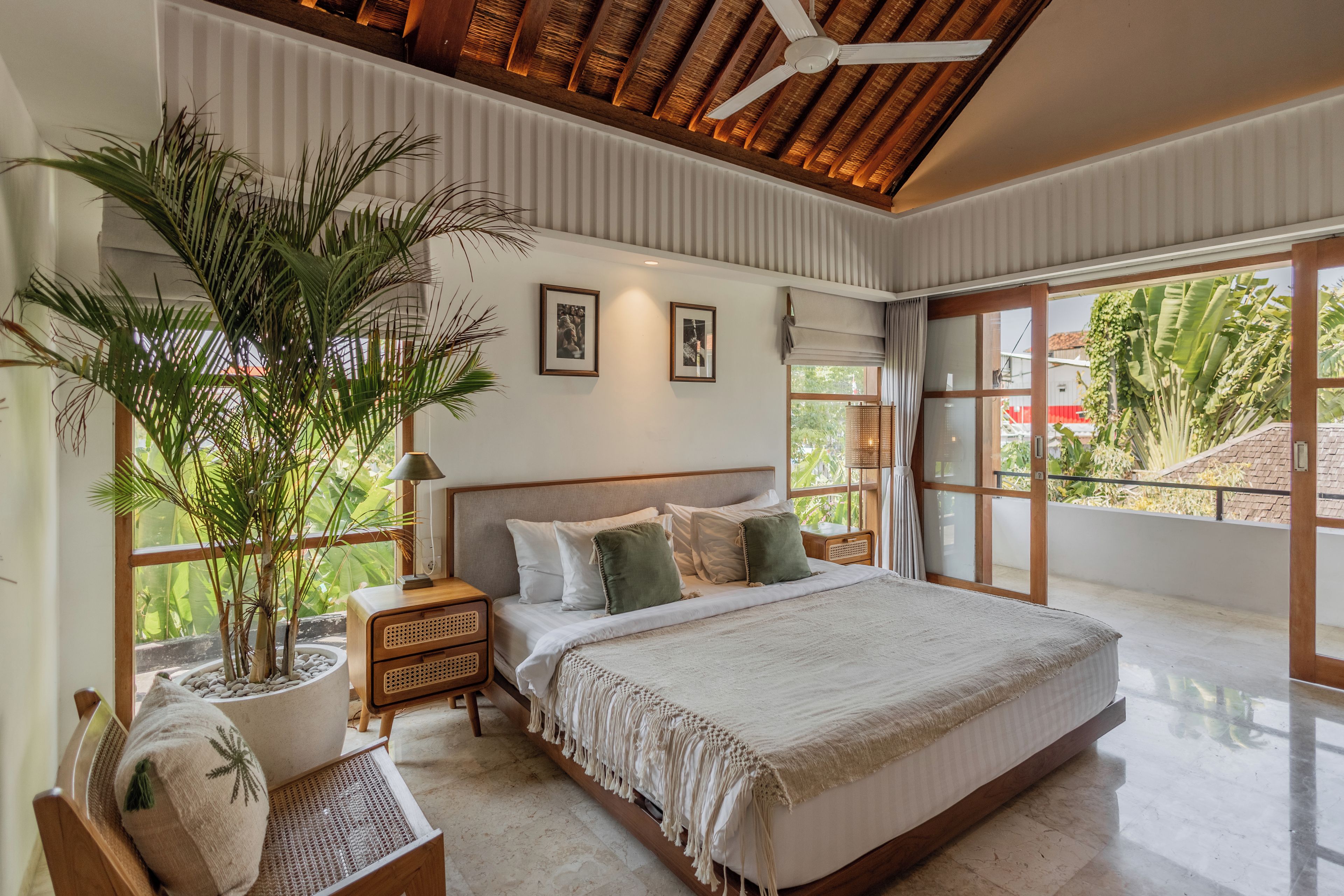 A spacious bedroom with a large bed, a ceiling fan, and a potted plant.