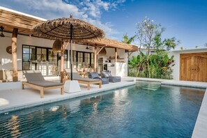 A modern pool area with lounge chairs and a thatched umbrella. - Villa Ruta I (Tabanan)