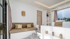 Een moderne hotelkamer met een bank, een kleine trap, een plank met decoratieve objecten en uitzicht op het groen.