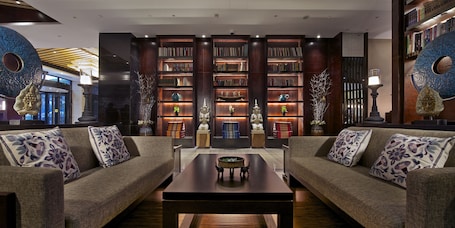 A modern living room with two sofas, a coffee table, and a bookshelf filled with books.