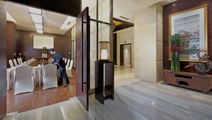 A modern hotel lobby with a conference room, a reception desk, and a decorative wall with a framed artwork. - SSAW Boutique Hotel Shanghai Hongkou (Shanghai)