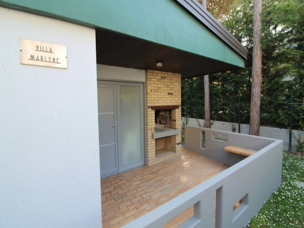 A villa named "Villa Marlene" with a brick fireplace and a covered patio area.