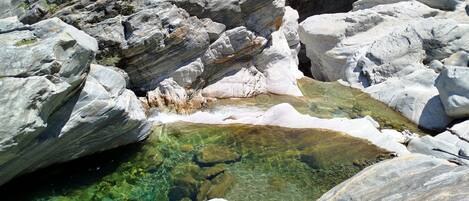 A rocky landscape with clear water pools and large boulders.