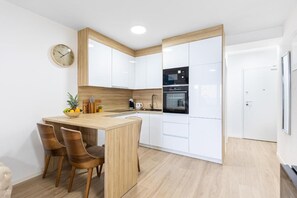 Enjoy cooking in this well-equipped kitchen with a central island, white cabinetry, and a black oven.