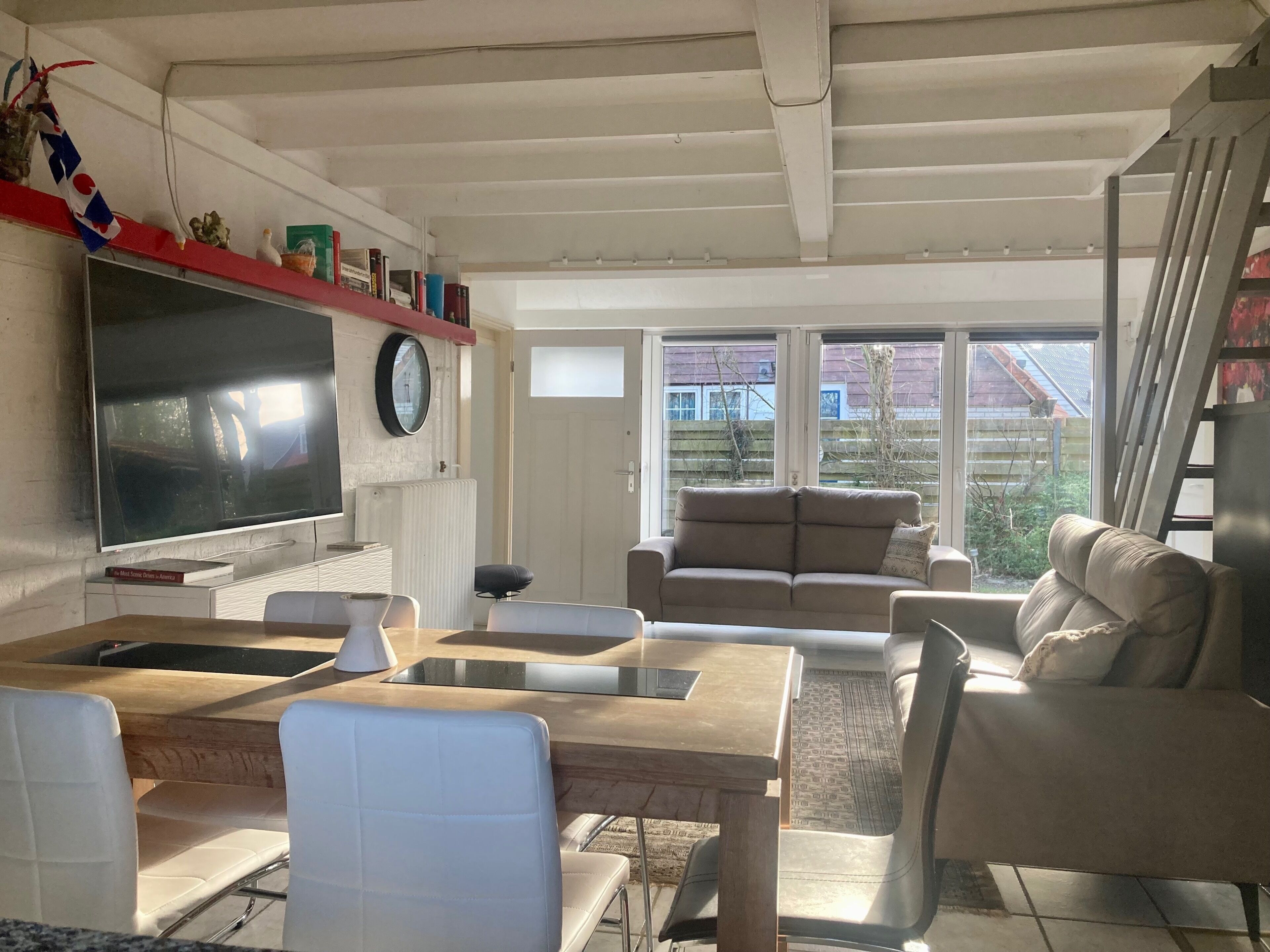 Een woonkamer met een televisie, bank, stoelen en een eettafel.