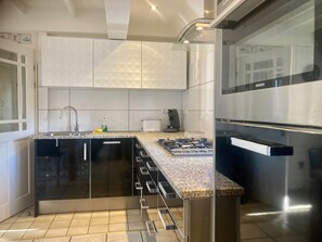 A modern kitchen with a stainless steel refrigerator, a built-in oven, a gas stove, and a sink.