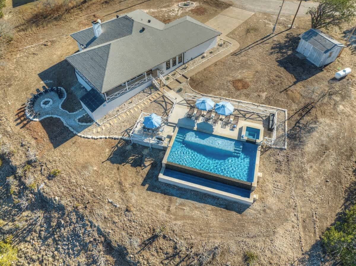 Vista aérea de una propiedad residencial con piscina, terraza techada y garaje independiente.