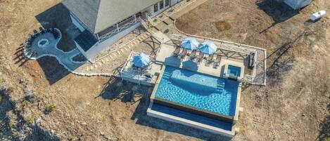 Vista aérea de una propiedad residencial con piscina, terraza techada y garaje independiente.