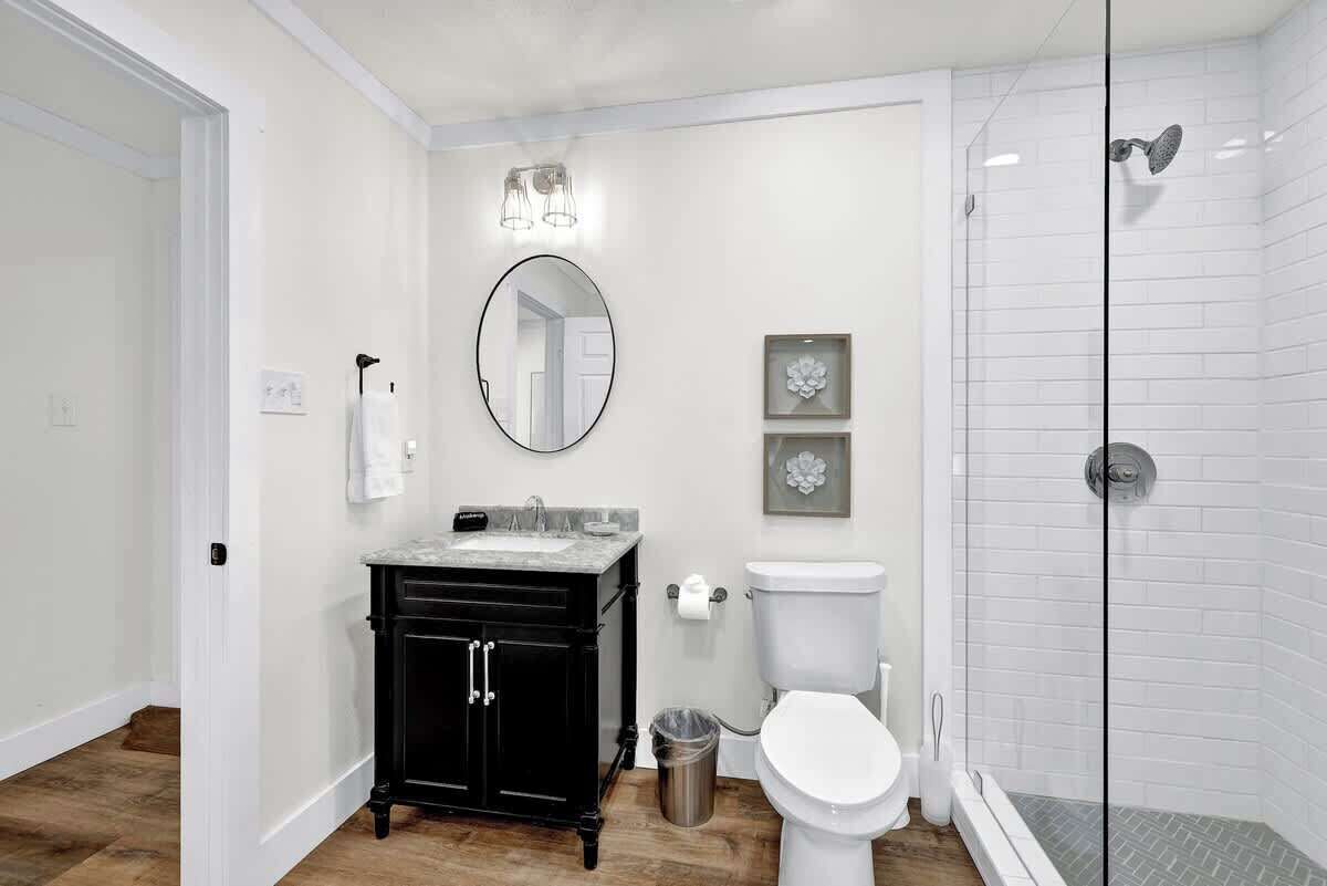 A bathroom with a black vanity, white toilet, and a glass shower enclosure.
