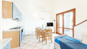 A compact kitchen with a dining area and a small sleeping area.