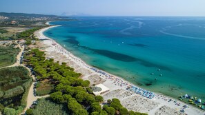 An aerial view of a beach with a long stretch of sand, trees, and a clear blue sea. - Simple Gem of Le Dimore di Budoni 2 Bedroom Trilo6 Apartment Sleeps 6 Persons (Budoni)
