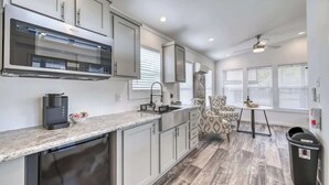 A modern kitchen with white cabinetry, a built-in oven, and a dining area with a patterned chair and table. - Resort at Fredericksburg Unit 14 (Fredericksburg)
