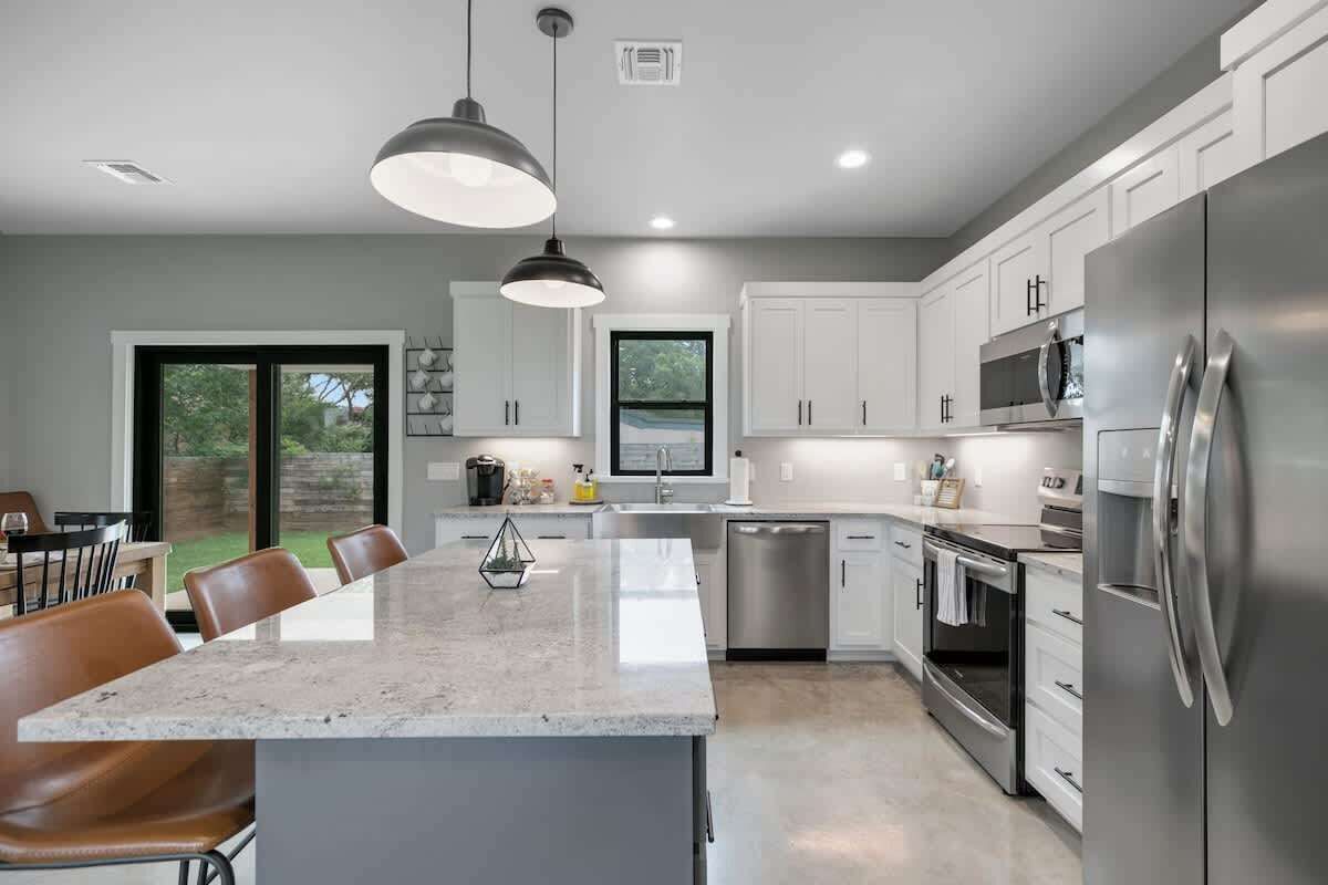 A modern kitchen with white cabinets, stainless steel appliances, and a large island with seating.