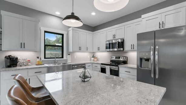 A modern kitchen with white cabinetry, stainless steel appliances, and a large island. - Luxury Home 3blck From Main St With Firepit (Fredericksburg)