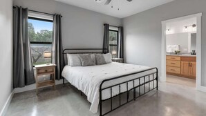 A bedroom with a bed, bedside tables, a ceiling fan, and a view of the outdoors. - Luxury Home 3blck From Main St With Firepit (Fredericksburg)