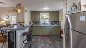 A modern kitchen with a central island, stainless steel appliances, and a view to the outside.