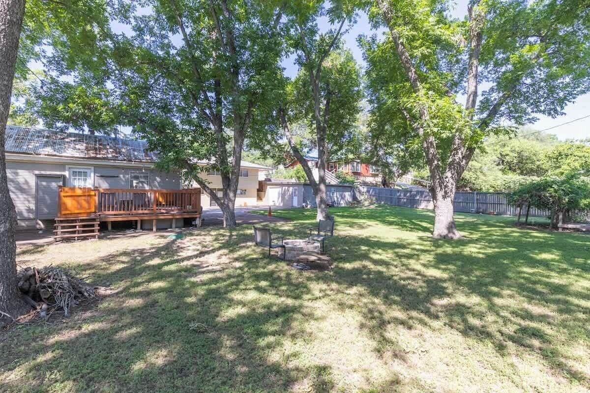 A backyard with a wooden deck, a fire pit, and a trampoline.