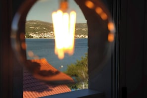 En utsikt från ett fönster över en kuststad med hus och en vattenyta.