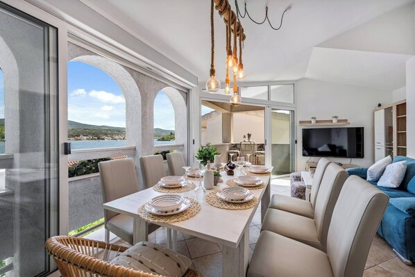 A dining area with a table set for four, a sofa, and a TV in the background.
