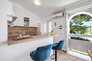 A modern kitchen with white cabinets, a wooden countertop, and a bar area with blue chairs.