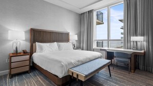Et hotelværelse med en stor seng, et skrivebord og udsigt over byen.