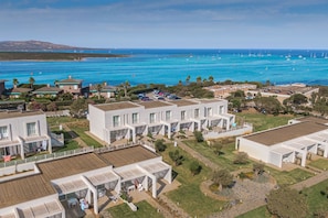 A coastal residential area with modern white houses, a marina with sailboats, and a clear view of the ocean. - Stunning Capo Falcone Apartments 2bedapt Sleeps 6 (Stintino)