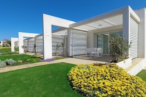 A modern building with a covered patio area, outdoor seating, and well-maintained landscaping. - Stunning Capo Falcone Apartments 2bedapt Sleeps 6 (Stintino)