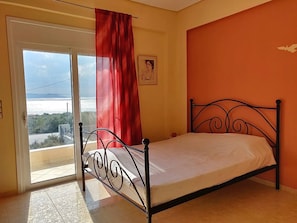 A bedroom with a bed, a window with a view, and a red curtain. - Dimitris Vasos Villa With Sea And Mountain View (Kymi-Aliveri)