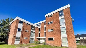 A two-story brick apartment building with a flat roof, large windows, and a small front garden. - 1 Bed Apartment, Sleeps 2, Free Parking, Tv (Enfield)
