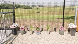 A fenced outdoor area with a gravel path and potted plants. - Peter's Farmhouse (Cookstown)