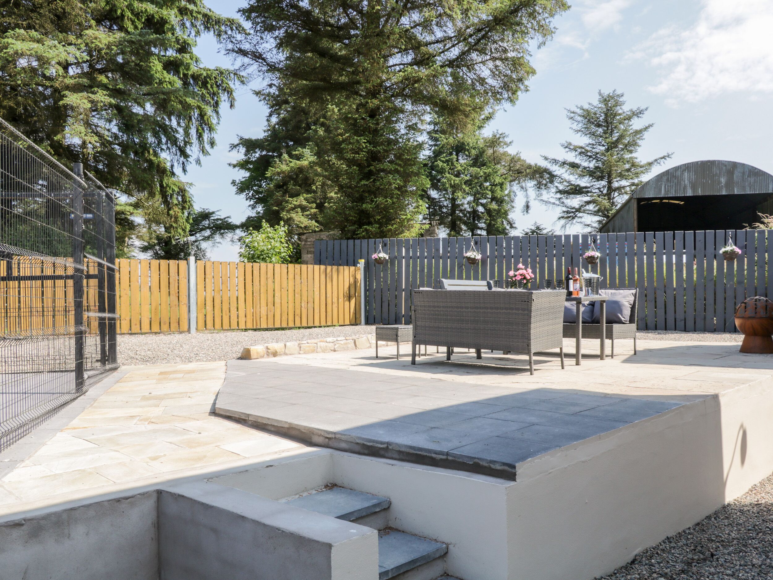 Un espace patio aménagé avec du mobilier d’extérieur, un banc en béton et une clôture en bois.