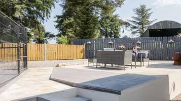 Un espace patio aménagé avec du mobilier d’extérieur, un banc en béton et une clôture en bois.